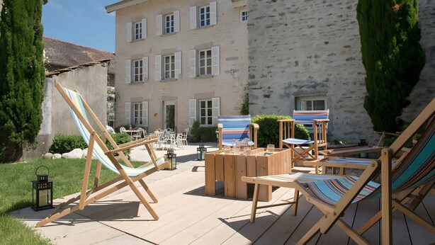 Une cour avec des sièges extérieurs, un hamac et un bâtiment doté de nombreuses fenêtres.