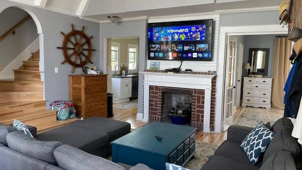 A living room with a fireplace, a television, and a staircase. - 3-bedroom house in charming Ocean City with AC for relaxing stays (Ocean City)