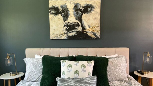 A bedroom with a large painting of a cow, a tufted headboard, and a bed with patterned bedding and decorative pillows. - 11, Peaceful retreat in Vermont (Manchester)