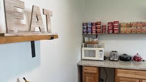 A kitchen with wooden cabinets, a microwave, toaster, and a shelf with canned goods. - 3, cozy pet friendly Vermont retreat - two doubles (Manchester)