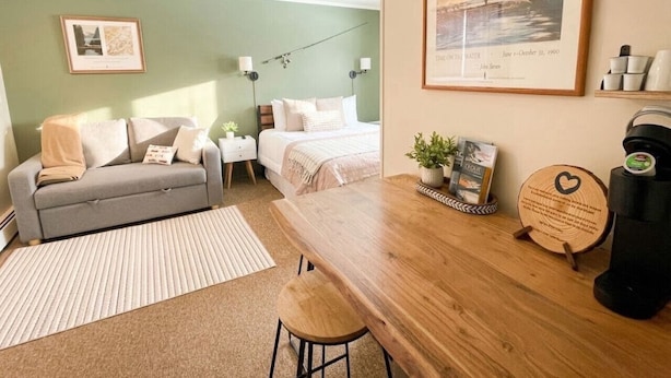 A cozy room with a bed, a sofa, a wooden table, and a coffee machine. - 3, cozy pet friendly Vermont retreat - two doubles (Manchester)