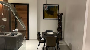 Een moderne eetruimte met een glazen scheidingswand, een trap en een eettafel met stoelen.
