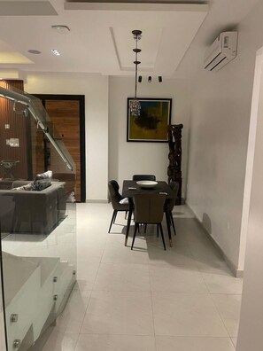 A modern dining area with a glass partition, a staircase, and a dining table with chairs. - Yaba PentHouse Apt 2B2B with Security and Lift and Generator (Lagos)