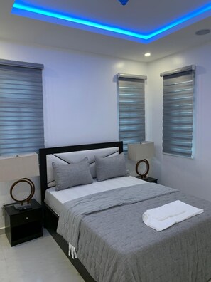 A modern bedroom with a bed, bedside lamps, and a ceiling light fixture. - Yaba PentHouse Apt 2B2B with Security and Lift and Generator (Lagos)