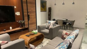Een moderne woonkamer met een zithoek, een salontafel, een televisie en een eethoek.