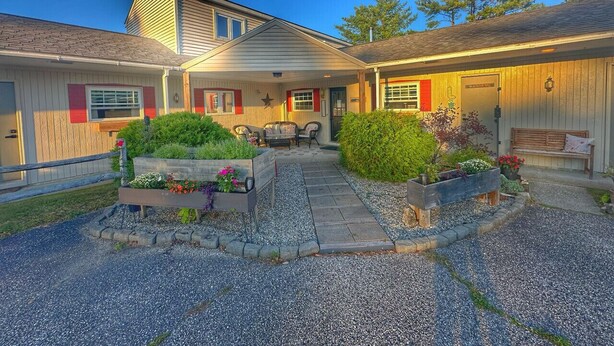 A two-story house with a covered patio area, a small outdoor seating area, and a gravel driveway. - Room 2, double room - sleeps 4 (Manchester)