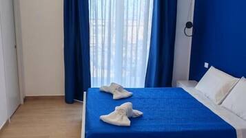 Une chambre d’hôtel avec un lit, des rideaux bleus et une vue par la fenêtre.