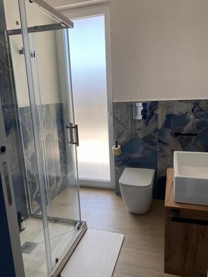 Ein modernes Badezimmer mit Duschkabine aus Glas, Toilette und Waschbecken.