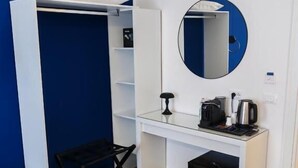 A compact room with a white desk, a black chair, a small black trash bin, and a round mirror on the wall. - Mare Suite (Palermo)