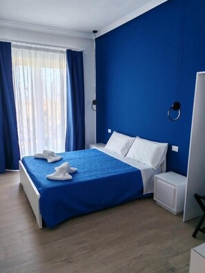 Ein Hotelzimmer mit einem großen Bett, weißen Kissen und blauen Vorhängen.