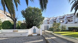 A courtyard with a tiled monument, gravel paths, and a well-maintained lawn. - JARDINS I BX 27 Roses / Roses - INTERimmo (Rosas / Roses)