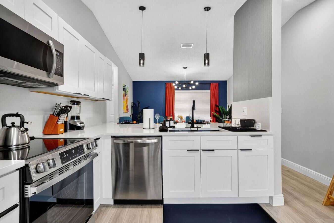 Una cocina moderna con armarios blancos, electrodomésticos de acero inoxidable y una isla central.