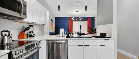 Una cocina moderna con armarios blancos, electrodomésticos de acero inoxidable y una isla central.
