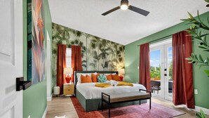 Ein Schlafzimmer mit Bett, Nachttischen, Deckenventilator und Blick durch die Glastür.