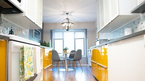 A kitchen with a dining table and chairs, a chandelier, and a window with blinds.
