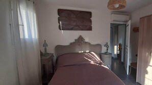 A bedroom with a bed, bedside tables, a lamp, a mirror, and a wardrobe. - House Swap Porticcio Sea View (Grosseto-Prugna)