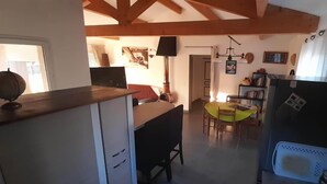 A kitchen with wooden beams, a dining table with chairs, a refrigerator, and a small island with a sink. - House Swap Porticcio Sea View (Grosseto-Prugna)