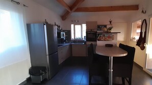 A compact kitchen with a dining area, a refrigerator, a microwave, and a sink. - House Swap Porticcio Sea View (Grosseto-Prugna)