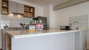 Eine moderne Küche mit weißen Schränken, einem Edelstahlkühlschrank und einer Kochinsel mit zwei Wasserflaschen.