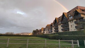 A residential building with multiple balconies and a grassy area in front. - Charming seafront apartment in Deauville (Tourgéville)