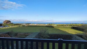 A coastal view with a grassy area, a building, and a clear sky. - Charming seafront apartment in Deauville (Tourgéville)