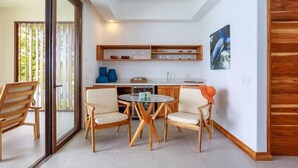 A modern kitchen with wooden cabinets, a glass dining table, and chairs. - Arenas del Mar Beachfront & Rainforest Resort (Quepos)