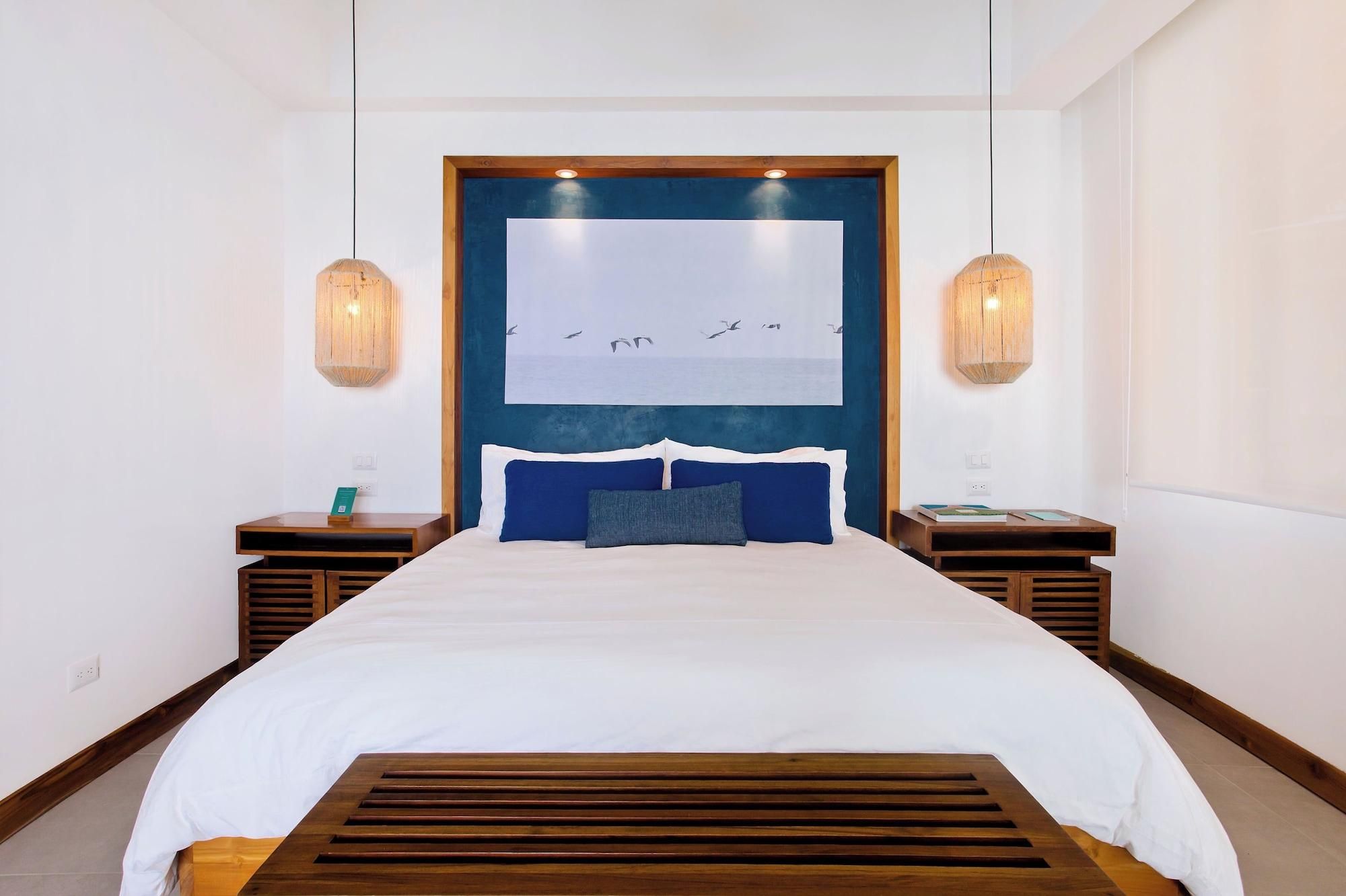 A hotel room with a large bed, wooden headboard, two bedside tables, and a wall-mounted artwork.