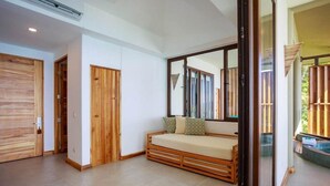 A bedroom with a wooden bed, a large mirror, and a sliding glass door leading to a balcony. - Arenas del Mar Beachfront & Rainforest Resort (Quepos)