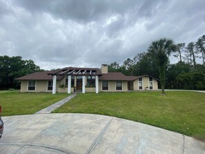 A two-story house with a covered porch, a front lawn, and a driveway. -  Retreat Style 6BR Home for Families & Groups (Seffner)