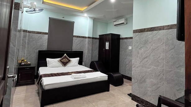 Una habitación de hotel con cama, mesita de noche, armario y escritorio con silla.
