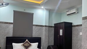 Una habitación de hotel con cama, armario, aire acondicionado y ventilador de techo.