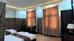 Habitación de hotel con dos camas, un escritorio, una silla y un televisor.