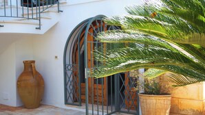 A courtyard with a large vase, a metal gate, and potted plants. - Charming home with private entrance in historic villa – quiet & idyllic (Ostuni)