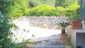 A stone staircase leading to a stone wall, surrounded by potted plants and greenery. - Charming home with private entrance in historic villa – quiet & idyllic (Ostuni)