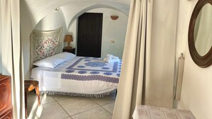 A bedroom with a bed, a nightstand, a lamp, a mirror, and a door. - Charming home with private entrance in historic villa – quiet & idyllic (Ostuni)