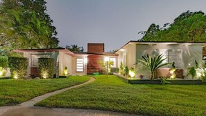A modern house with a well-maintained lawn, a pathway leading to the entrance, and a brick chimney. - Villa Oahu Basketball Fire Pit Mini Golf (North Miami Beach)