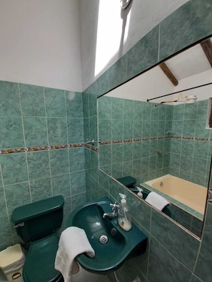 A bathroom with green tiles, a sink, a toilet, and a bathtub. - Cabaña Lewana Campestre (Villa de Leyva)