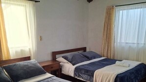 A room with two beds, wooden beams on the ceiling, and a window with curtains. - Cabaña Lewana Campestre (Villa de Leyva)