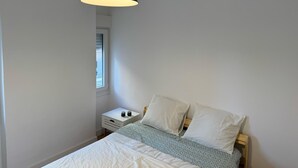 A bedroom with a bed, bedside table, and a hanging light fixture. - Single room for rent for single days or weekends. (Sevilla este)