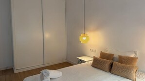 A bedroom with a bed, white bedding, a hanging lamp, and a wardrobe. - Single room for rent for single days or weekends. (Sevilla este)
