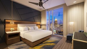 A modern hotel room with a large bed, a desk, and a city view.