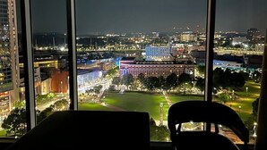 A view from a window with a cityscape at night, including buildings and a park.