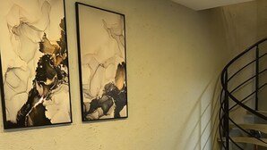 Een moderne woonkamer met een bank, een bijzettafeltje en twee abstracte schilderijen aan de muur.
