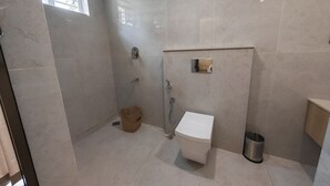 A modern bathroom with a toilet, shower, and sink. - The Zen Retreat (Kozhikode)