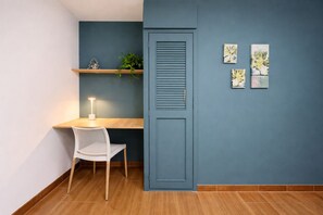 Ein Zimmer mit Schreibtisch, Stuhl und einer blauen Wand mit Kunstwerken.