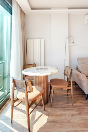 Ein modernes Zimmer mit einem runden Holztisch, zwei Stühlen, einer Couch und einer Stehlampe.