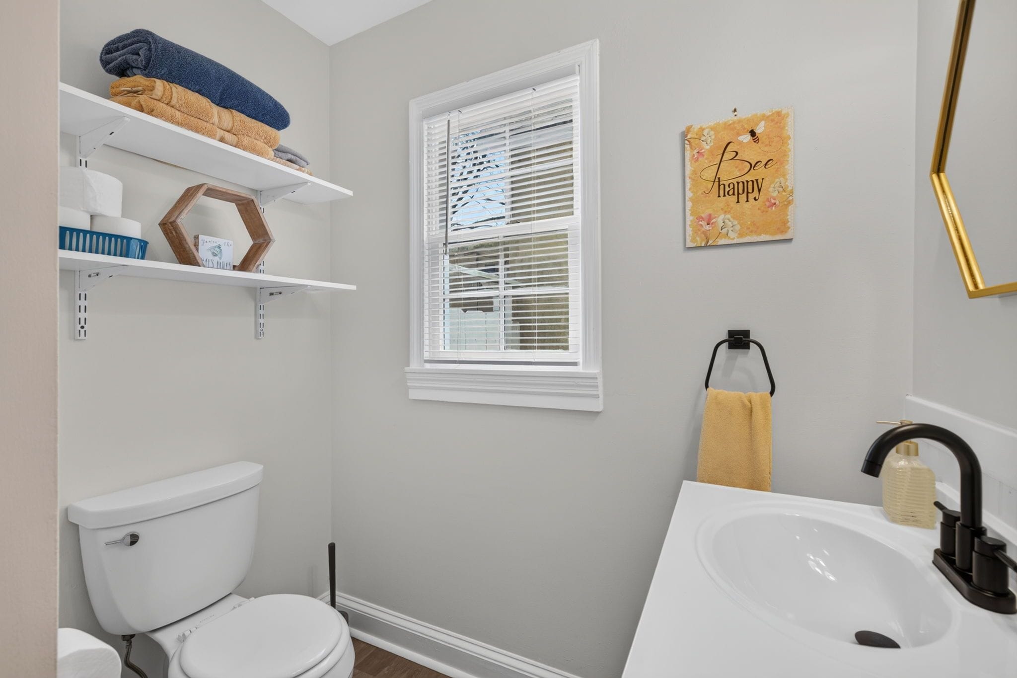 Une salle de bain avec des toilettes, un lavabo et des étagères où sont rangées les serviettes.