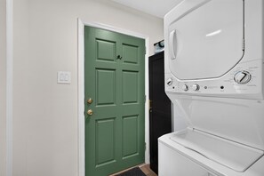A laundry room with a green door, a white washing machine, and a dryer. - Historic Cottage | Walk to Forsyth | King + Queen (Savannah)