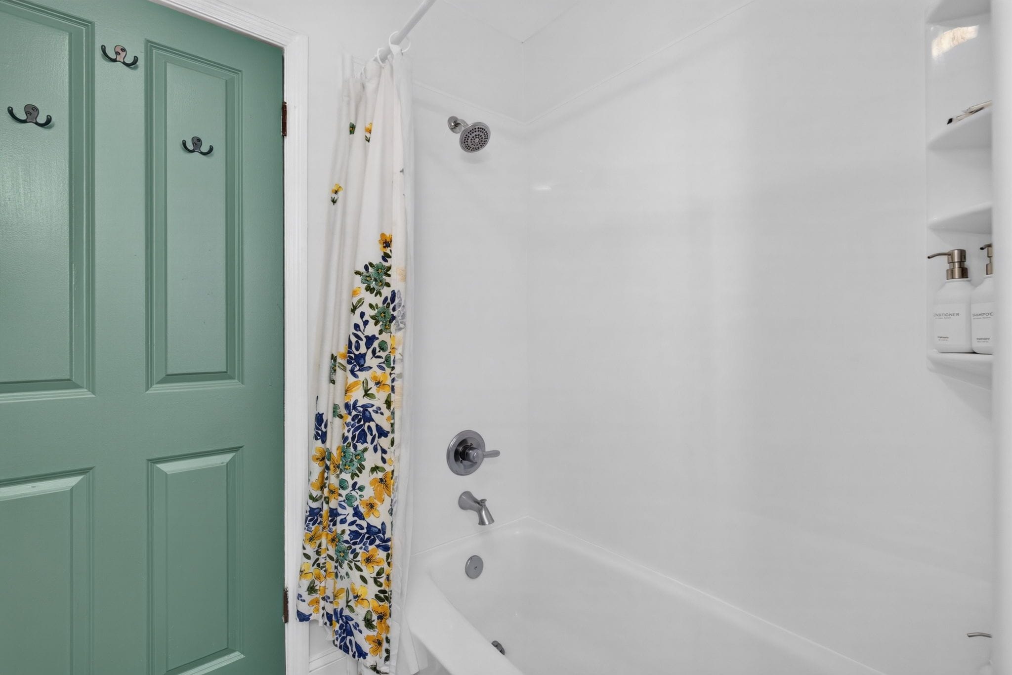 A bathroom with a green door, a shower with a white curtain, and a bathtub.