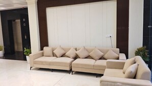 Ein beigefarbenes Ecksofa in einer modernen Lobby mit weißer Wand und Holzvertäfelung.